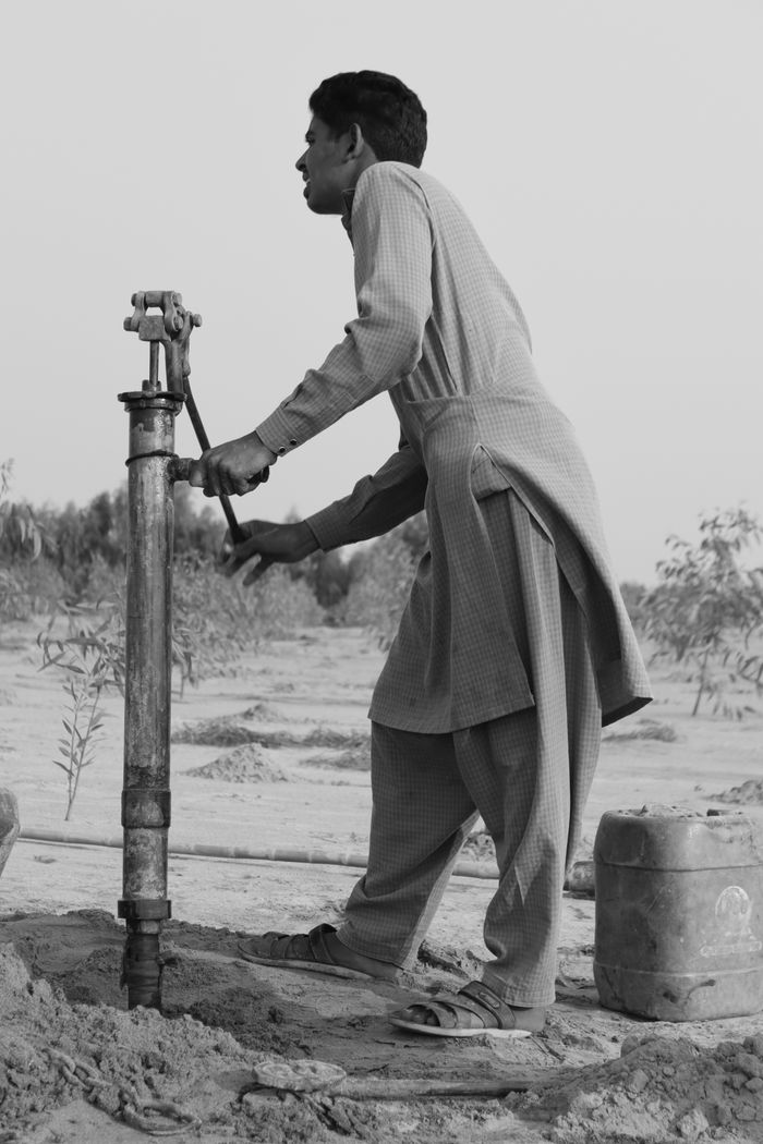 our-vission A man using a hand pump in a rural setting, symbolizing life's simplicity and resilience.
